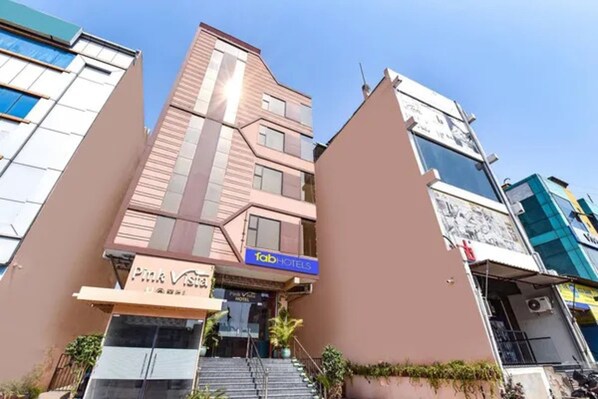 Un hotel de diseño moderno, con un cartel llamativo de 'Fab Hotels' y un cartel de 'Pink Vista' debajo.