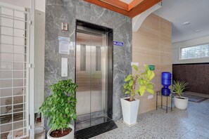 Un ascenseur avec un panneau indiquant qu’il est réservé au personnel, un distributeur d’eau et des plantes en pot.