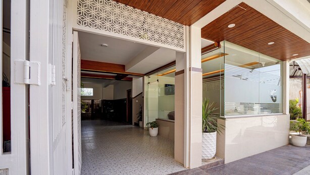 A modern building entrance with a geometric decorative panel, a glass door, and potted plants. - Fabhotel Global Stay (Bangalore)