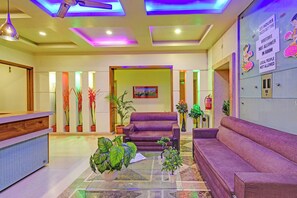 A reception area with a reception desk, purple sofas, and potted plants. - Via Log Inn - Ameerpet Metro Station, Ameerpet (Hyderabad)