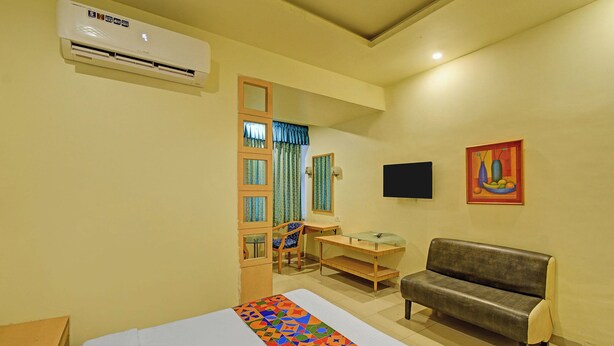 A room with a bed, a sofa, a desk, a chair, a TV, and an air conditioning unit. - Via Log Inn - Ameerpet Metro Station, Ameerpet (Hyderabad)