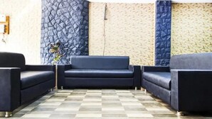 Un área de recepción con piso a cuadros, un sofá azul oscuro y una pared con textura.