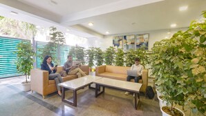 Eine moderne Lobby mit Sitzbereichen, Topfpflanzen und Kunstwerken an den Wänden.