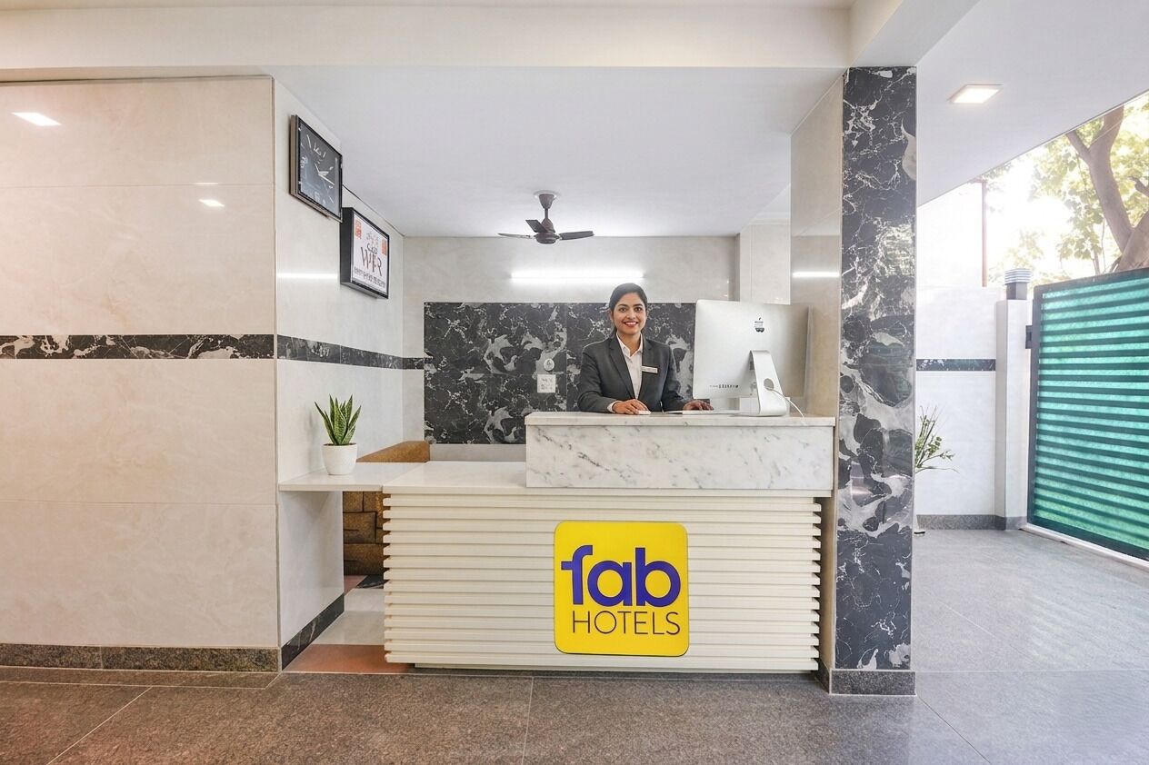 A hotel reception desk with a marble counter, a clock, and a sign indicating WiFi availability.