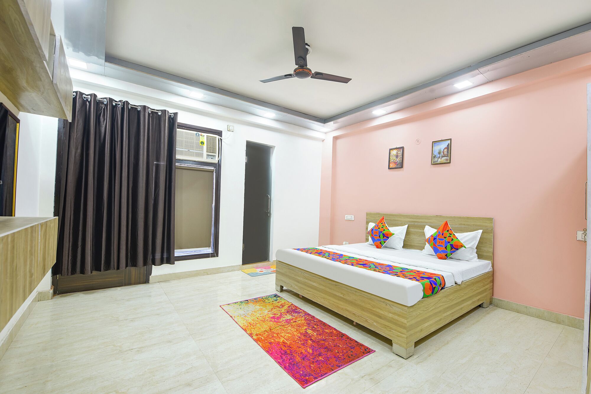 A bedroom with a bed, a ceiling fan, a window with curtains, and a door.