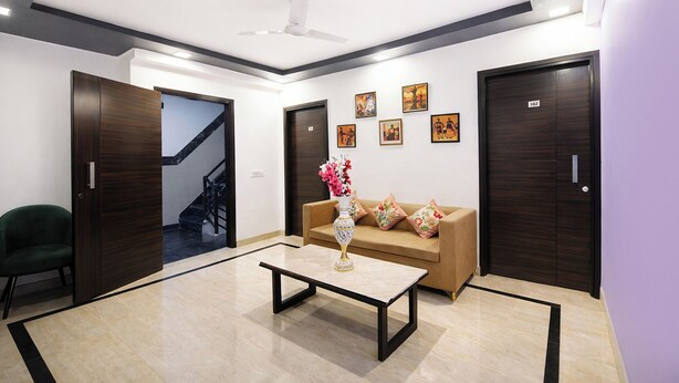 Eine moderne Lobby mit einer Couch, einem Couchtisch, einer Vase mit Blumen und einer Treppe.
