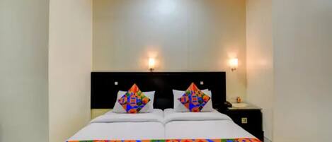 Un letto matrimoniale con una coperta colorata a motivi geometrici, due cuscini coordinati, una testiera nera e due luci a parete.