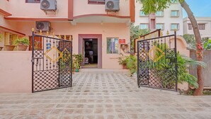Un bâtiment doté d’une entrée pavée, de deux unités de climatisation et d’une enseigne indiquant si des chambres sont disponibles pour les clients.