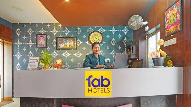 Un comptoir d’accueil avec une horloge, un ventilateur et une enseigne indiquant « Aditya 3 Guesthouse ».