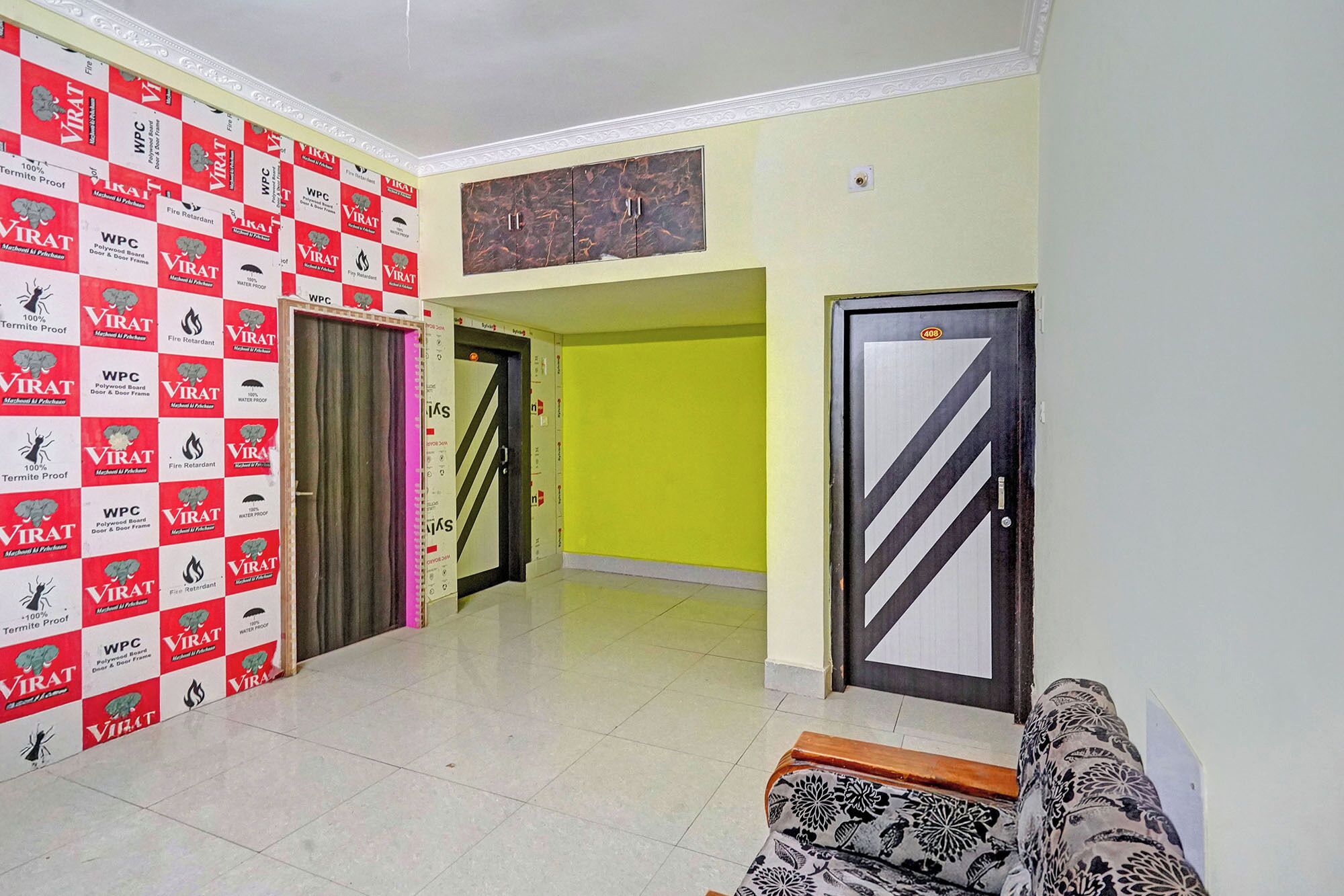 Un pasillo con un estampado de cuadros en la pared, una puerta con diseño a rayas blancas y negras, y un sofá en primer plano.