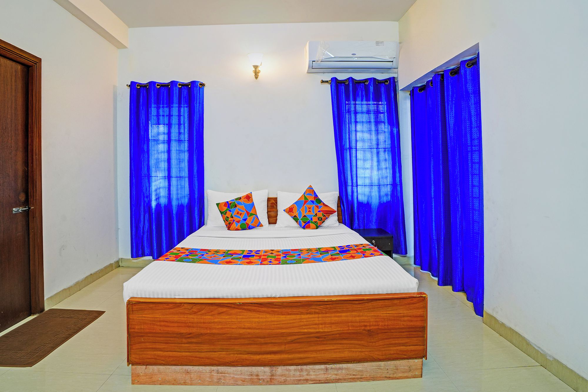 Una habitación de hotel con una cama de madera, ropa de cama blanca y cortinas azules.