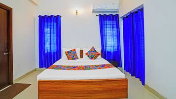 Una habitación de hotel con una cama de madera, ropa de cama blanca y cortinas azules.