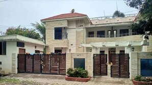 Un edificio residencial de dos pisos con techo de tejas rojas, entrada con reja y un pequeño balcón.