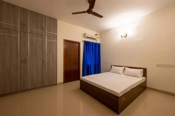 A bedroom with a bed, wardrobe, ceiling fan, and an air conditioning unit. - Fabhotel Nayana Square (Chennai)