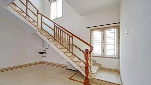 Una habitación amplia con una escalera de madera y un ventanal grande.