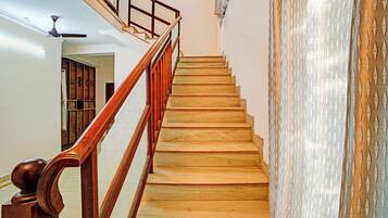 A wooden staircase with a handrail, leading to a landing with a ceiling fan.
