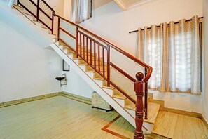 A staircase with wooden balusters and a handrail, leading to an upper floor. - Fabhotel Nayana Square (Chennai)