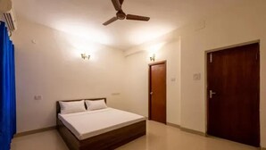 Un dormitorio con cama, ventilador de techo, puerta y lámpara en la pared.