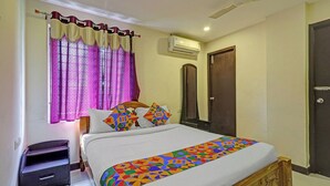 A bedroom with a bed, curtains, an air conditioning unit, a mirror, and a door. - Fabhotel Neha (Chennai)