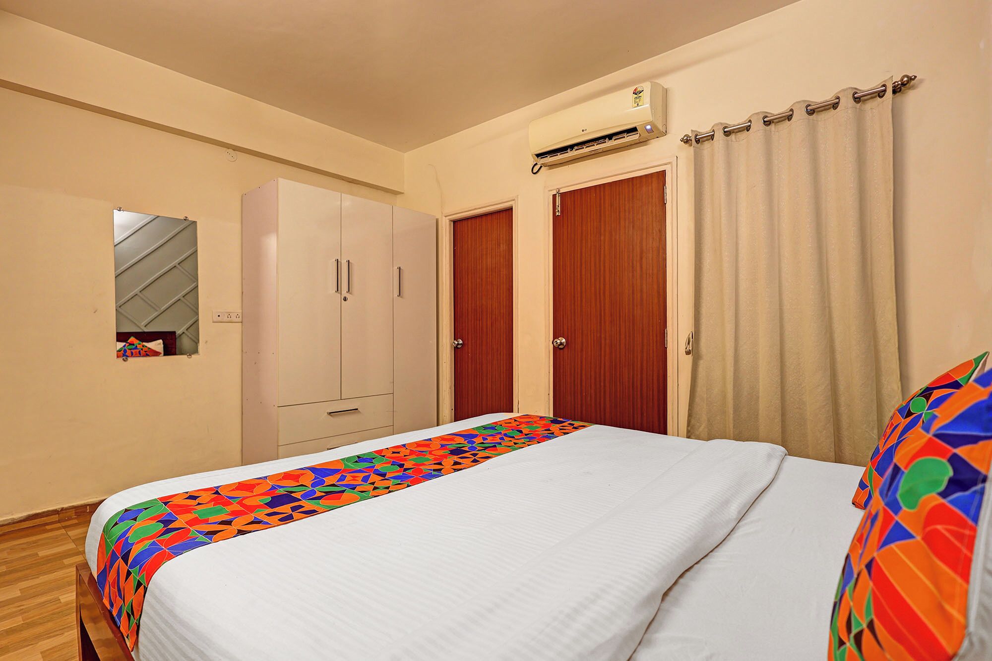 A bedroom with a bed, a wardrobe, a mirror, and an air conditioning unit.