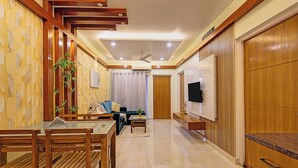 Una sala de estar moderna con comedor, paneles de madera, ventilador de techo y televisor de pantalla plana montado en la pared.