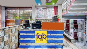 Uma área de recepção com design moderno, incluindo um ventilador de teto, uma janela grande com vista e uma placa com a inscrição 'fab hotels'.