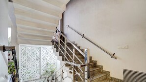 Uma escadaria com guarda-corpos e corrimão de metal, que leva a um patamar com um painel decorativo na parede.