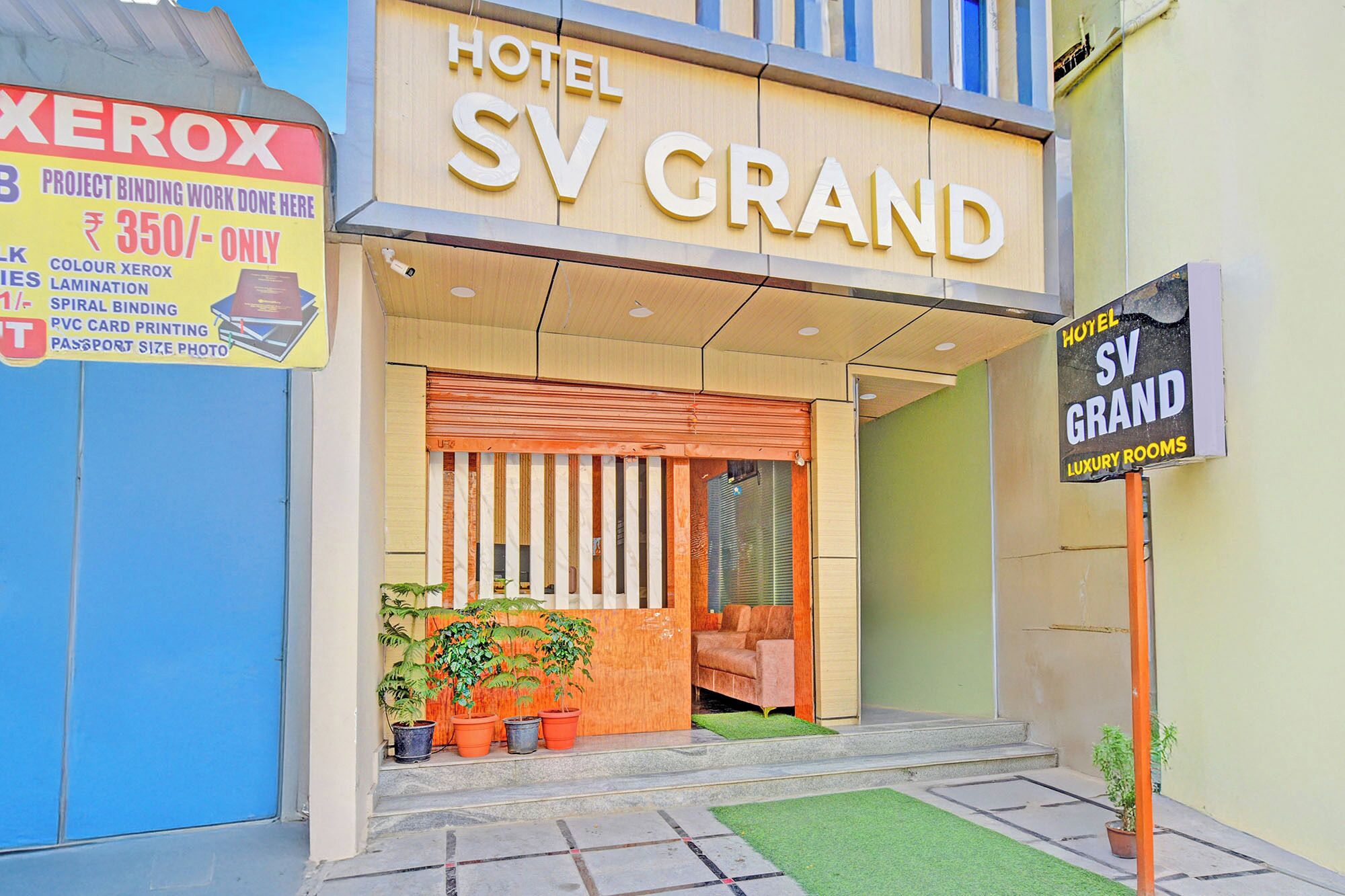 Ein Hotel Eingang mit einem Schild für Hotel SV Grand und einem Xerox-Schild, das Dienstleistungen anwirbt.