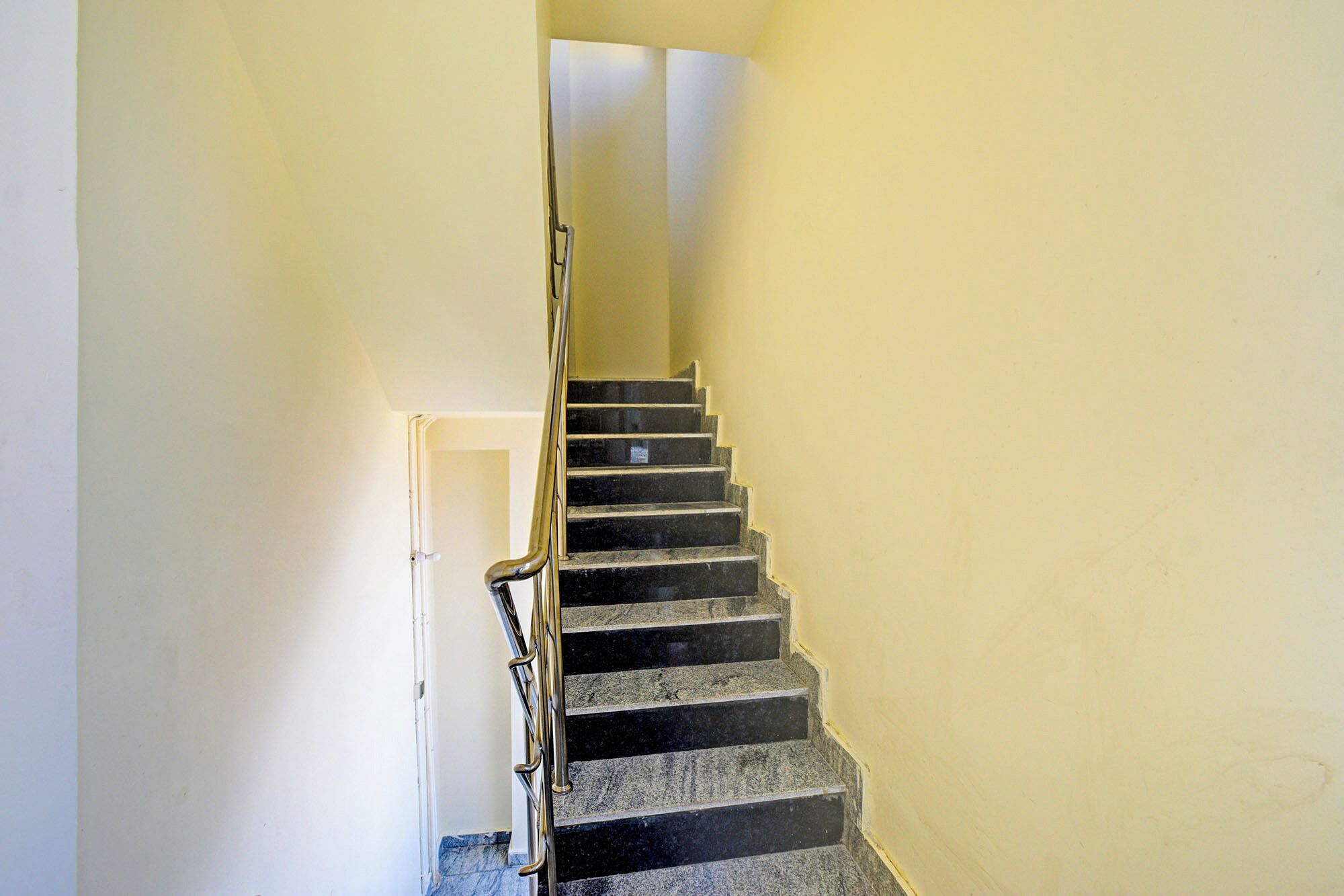 A staircase with a handrail, leading to a door at the top.