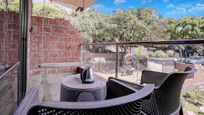 A balcony with a brick wall, a metal railing, and outdoor furniture. - Fabhotel Green Crystal (Mahabaleshwar)