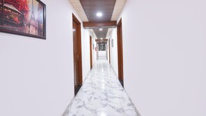 A corridor with wooden doors, white walls, and a marble floor. - Fabhotel Yatri Inn (Noida)