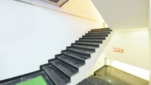 A staircase with black steps leading to a higher floor, a 'HOTEL' sign on the wall, and a ceiling with wooden panels. - Fabhotel Yatri Inn (Noida)