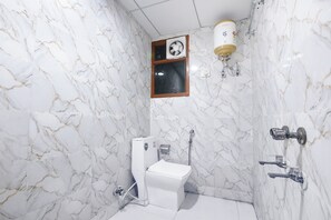 A bathroom with a toilet, a shower, a fan, and a water heater. - Fabhotel Yatri Inn (Noida)