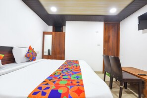 A hotel room with a bed, a desk, a chair, a wardrobe, and a television. - Fabhotel Yatri Inn (Noida)