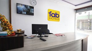 Ein Hotelrezeptionstresen mit einem Computermonitor, einer Uhr und einem Schild mit der Aufschrift 'Tab Hotels'.