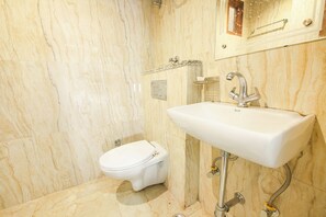 A bathroom with a marble wall, a white sink, and a toilet. - Fabhotel Neu-Nest (Rishikesh)