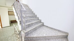 Eine Treppe mit Handlauf, Teppichstufen und einem Feuerlöscher an der Wand.