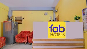 Een receptiebalie met 'fab hotels' bord, een koelkast, een bank en een wandkalender.