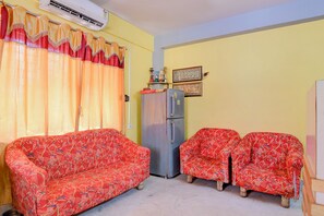 A compact living space with two sofas, a refrigerator, and decorative items on the wall.