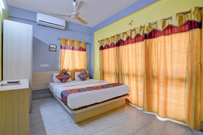 A bedroom with a bed, curtains, an air conditioner, and a ceiling fan. - Fabhotel Yellow Rose (Kolkata)