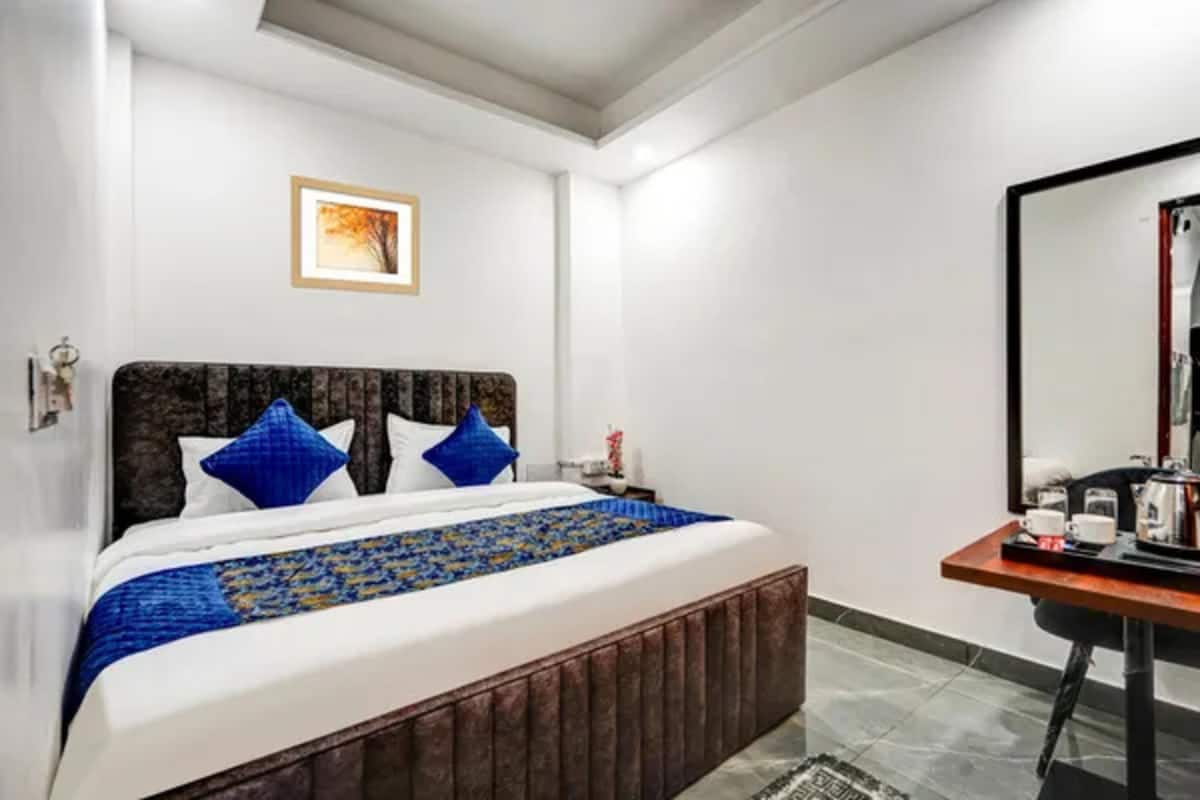 Habitación de hotel con una cama, una mesita de noche, un espejo y un cuadro en la pared.