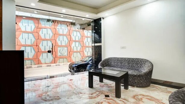 Ein modernes Interieur mit Marmorboden, Wandverkleidung mit Muster und einer Sitzecke mit Sofa und Tisch.