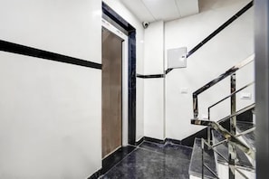 Interior moderno com uma escadaria de mármore, uma porta e um aplique na parede.