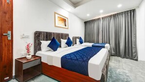 Ein Hotelzimmer mit einem großen Bett, einem hölzernen Kopfteil, einem Nachttisch mit Blumenvase und einem Fenster mit Vorhängen.