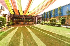 A courtyard with a lawn, a building with a balcony, and a blue wall with greenery.
