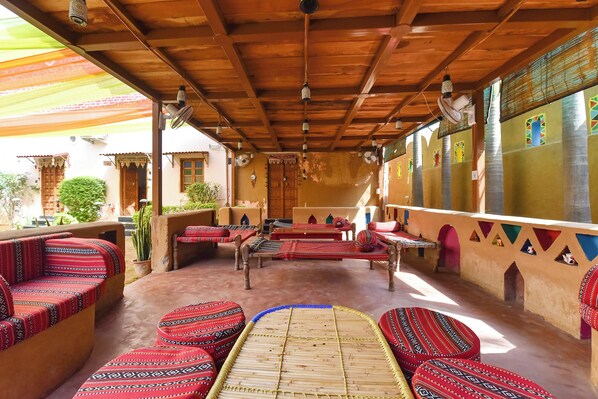 A traditional room with wooden beams, patterned cushions, and a central woven mat.