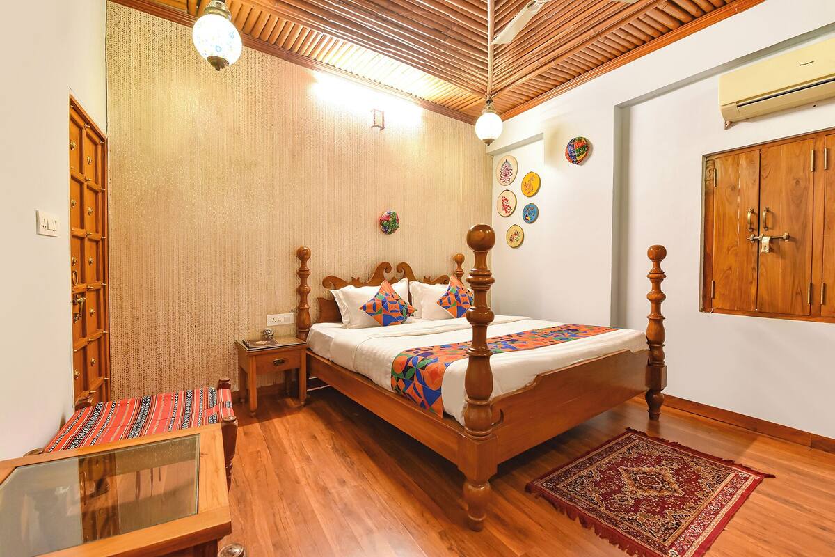 A traditional room with a wooden bed, a nightstand, a mirror, and a red rug.