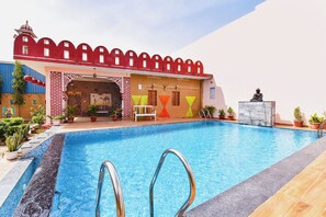 A swimming pool with a red-roofed structure, a Buddha statue, and potted plants. - Fabhotel Nimabal Dhani (Jaipur)