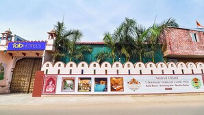 A hotel facade with a sign for 'fabHOTELS' and a banner advertising 'Nimbal Dhani Boutique Rajwadi Castle Stay' with amenities like 'Royal Rooms,' 'Swimming Pool,' and 'Bornefine Parties.' - Fabhotel Nimabal Dhani (Jaipur)