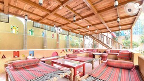 A traditional wooden structure with a covered patio, red patterned cushions, and a staircase leading to an upper level. - Fabhotel Nimabal Dhani (Jaipur)